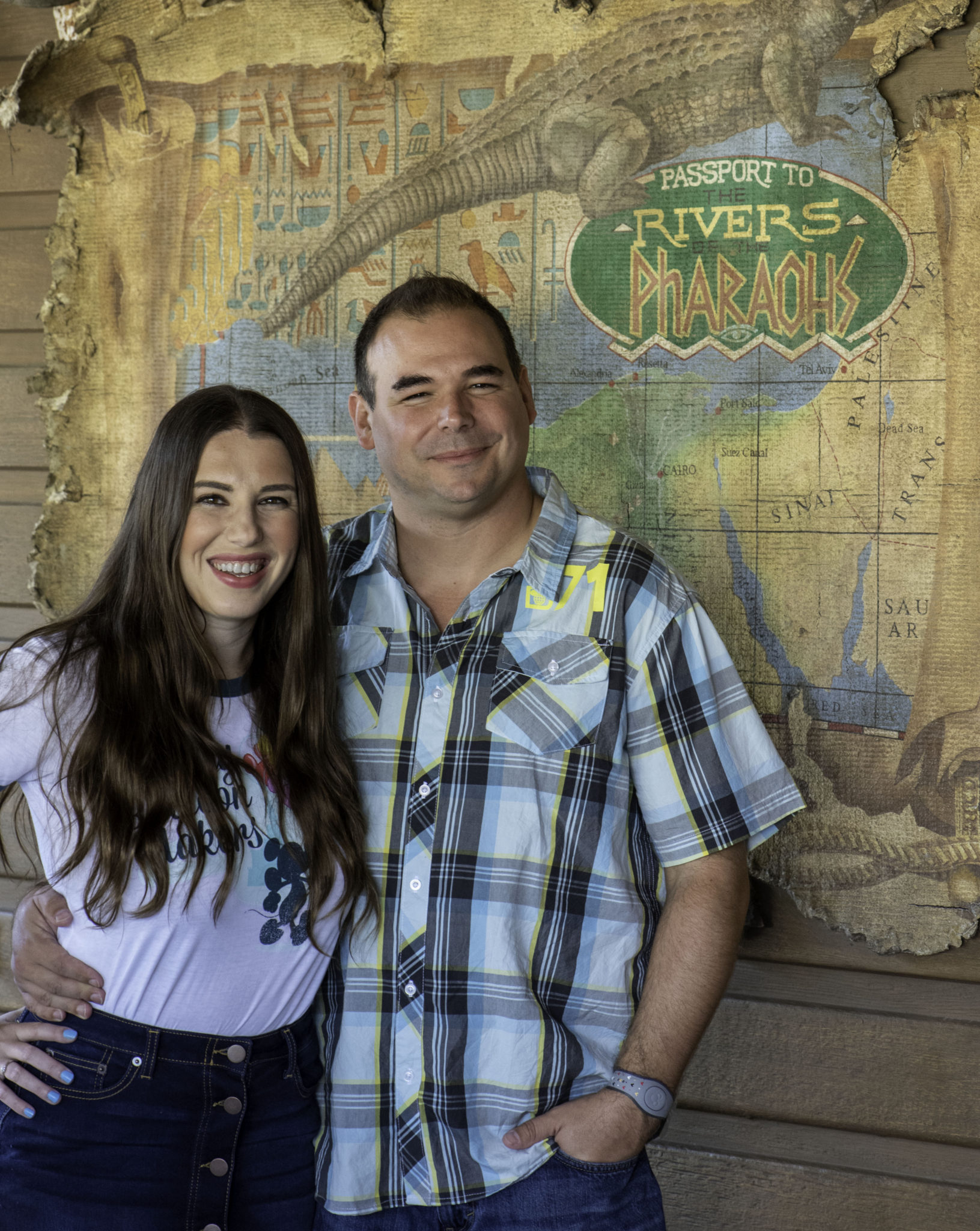 Chelsea and Jay standing in front of a Jungle Cruise map for their engagement photos.
